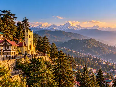 Historic neo-Gothic church on a Himalayan ridge with cedar forests and snow-capped peaks in the background.