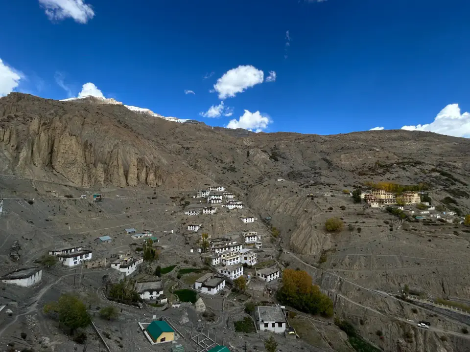 Terraced agricultural fields and traditional whitewashed village homes set against a steep mountainside.